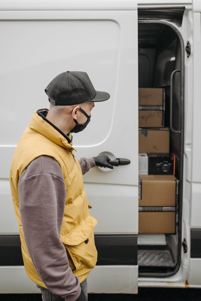 A courier in a yellow vest delivers packages from a van, emphasizing the new normal with safety protocols.